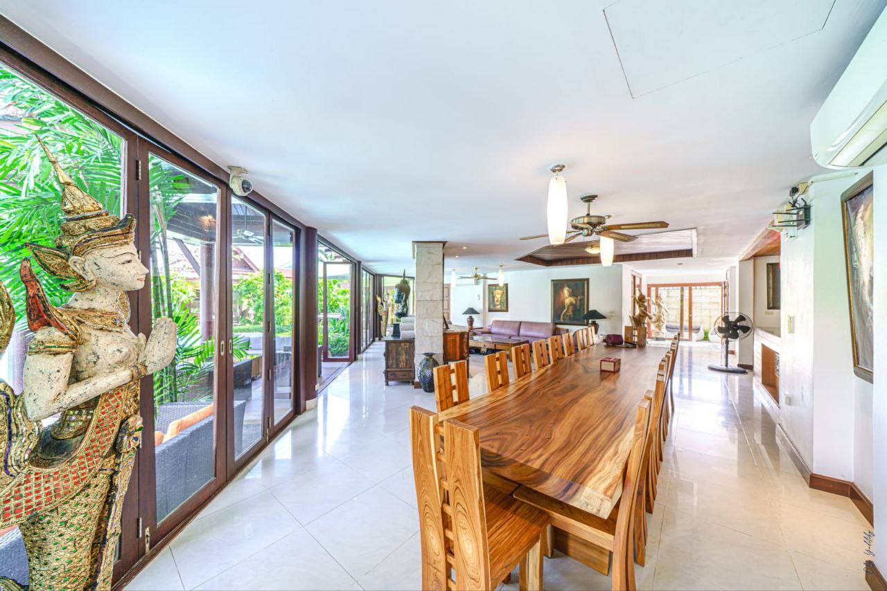 Spacious dining room with a long wooden table and Thai statue at The Himmaphan Phuket villa.